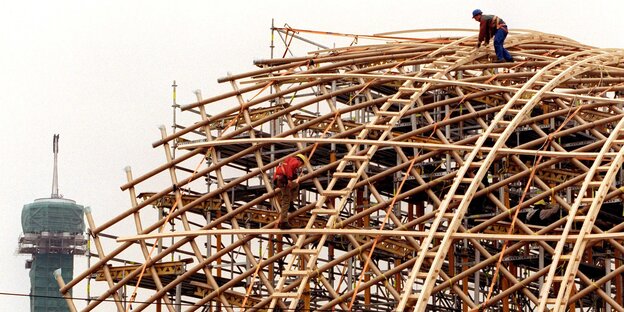 Zwei Menschen arbeiten an einer Holz-Konstruktion Zwei Menschen arbeiten an einer Holz-Konstruktion