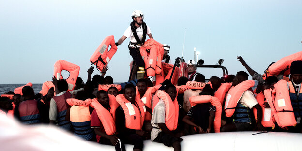 Im Mittelmeer gerettete Flüchtlinge sitzen an Bord der Aquarius unter einer Plane Im Mittelmeer gerettete Flüchtlinge sitzen an Bord der Aquarius unter einer Plane