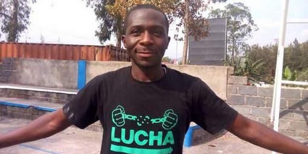 Ein Mann im schwarzen T-Shirt mit grüner Aufschrift breitet lächelnd beide Arme aus Ein Mann im schwarzen T-Shirt mit grüner Aufschrift breitet lächelnd beide Arme aus