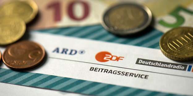 Geldscheine liegen auf einem Rundfunkbeitrag-Formular Geldscheine liegen auf einem Rundfunkbeitrag-Formular