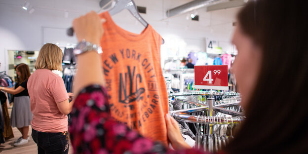 Eine Frau betrachtet ein organgenes Shirt Eine Frau betrachtet ein organgenes Shirt
