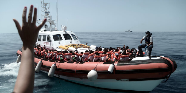 Flüchtlinge, ausgestattet mit Schwimmwesten, sitzen in einem Boot der italienischen Küstenwache Flüchtlinge, ausgestattet mit Schwimmwesten, sitzen in einem Boot der italienischen Küstenwache