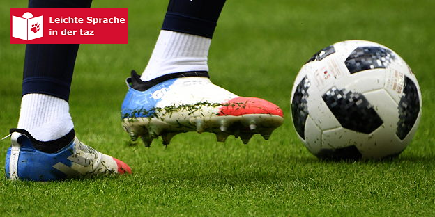 Zwei Füße in Stollenschuhe neben einem Ball Zwei Füße in Stollenschuhe neben einem Ball