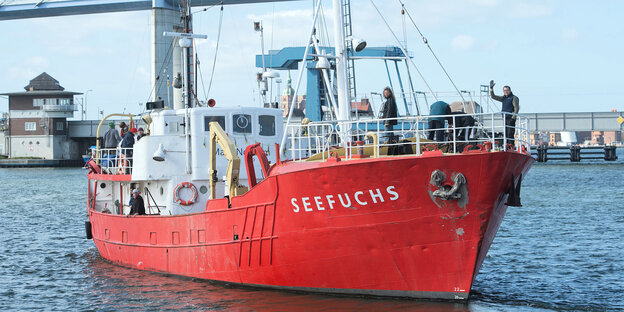Ein Schiff mit rotem Rumpf vor einer Brücke Ein Schiff mit rotem Rumpf vor einer Brücke