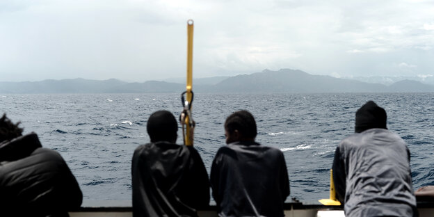 Flüchtlinge auf einem Boot schauen aufs Festland Flüchtlinge auf einem Boot schauen aufs Festland