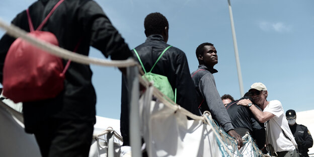 Männer verlassen das Schiff Aquarius im Hafen, einer wird zur Begrüßung umarmt Männer verlassen das Schiff Aquarius im Hafen, einer wird zur Begrüßung umarmt