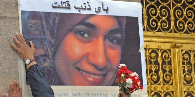 Vor dem Rathaus in Dresden kleben zwei Männer ein Foto der am 01.07.2009 im Dresdner Landgericht erstochenen Ägypterin Marwa El-Sherbini an die Wand Vor dem Rathaus in Dresden kleben zwei Männer ein Foto der am 01.07.2009 im Dresdner Landgericht erstochenen Ägypterin Marwa El-Sherbini an die Wand
