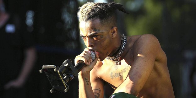 XXXTentacion mit freiem Oberkörper und einem Miko in der Hand XXXTentacion mit freiem Oberkörper und einem Miko in der Hand