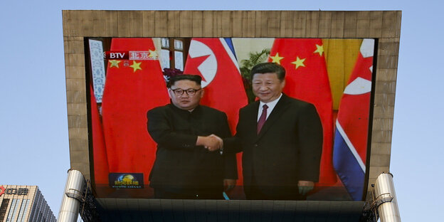 Ein riesiger Bildschirm, auf dem das Treffen von Kim Jong Un, Machthaber von Nordkorea, und Xi Jinping, Präsident von China, zu sehen ist Ein riesiger Bildschirm, auf dem das Treffen von Kim Jong Un, Machthaber von Nordkorea, und Xi Jinping, Präsident von China, zu sehen ist
