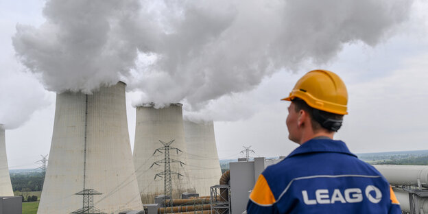 Paul Donath, Projektleiter der Sicherheitsbereitschaft, steht vor den dampfenden Kühltürmen des braunkohlekraftwerks Jänschwalde der Lausitz Energie Bergbau AG