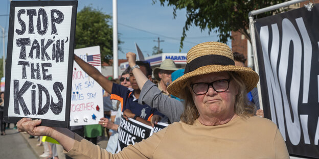 Eine Frau mit Transparent "Stop takin'our kids" Eine Frau mit Transparent "Stop takin'our kids"
