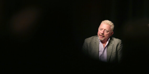 Boris Becker sitzt im grauen Jackett in völliger Schwärze Boris Becker sitzt im grauen Jackett in völliger Schwärze