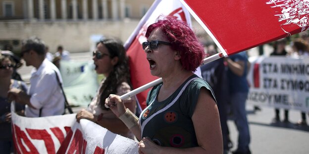 Eine Demonstrantin mit roten Haaren hält ein Transparent mit roter Schrift und eine rote Fahne Eine Demonstrantin mit roten Haaren hält ein Transparent mit roter Schrift und eine rote Fahne