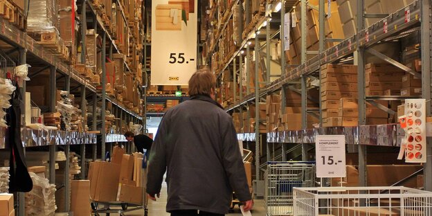 Ein Mann vor langen Ikea-Regalreihen Ein Mann vor langen Ikea-Regalreihen