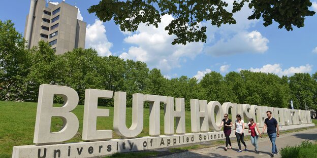 Studierende laufen vor dem Schriftzug Beuth-Hochschule durchs Grüne Studierende laufen vor dem Schriftzug Beuth-Hochschule durchs Grüne