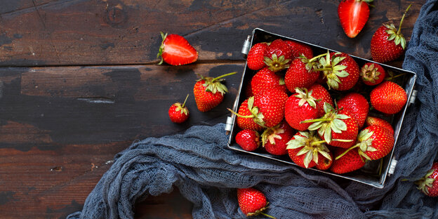 Erdbeeren in einer Schale, auf einem Tuch, auf einer Holzfläche Erdbeeren in einer Schale, auf einem Tuch, auf einer Holzfläche