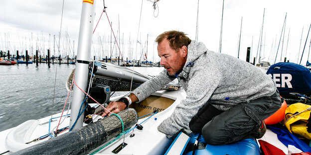 Heiko Kröger prüft auf seinem Segelboot die Leinen Heiko Kröger prüft auf seinem Segelboot die Leinen