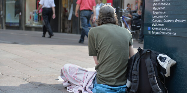 Ein Obdachloser sitzt auf dem Boden Ein Obdachloser sitzt auf dem Boden