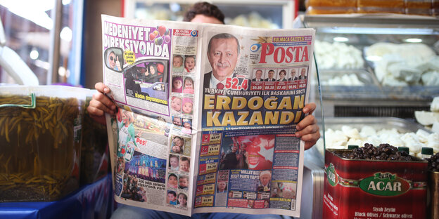 Ein Mann liest in einem Kiosk eine Tageszeitung Ein Mann liest in einem Kiosk eine Tageszeitung