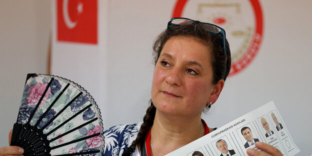 Türkei-Wahl in Deutschland - Frau hält Fächer und einen Wahlzettel in der Hand, hinter ihr die türkische Fahne Türkei-Wahl in Deutschland - Frau hält Fächer und einen Wahlzettel in der Hand, hinter ihr die türkische Fahne