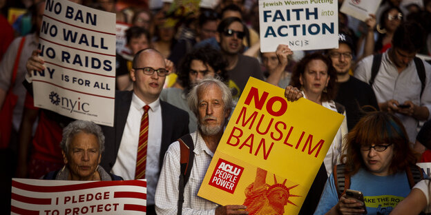 Menschen demonstrieren mit Plakaten gegen den "Muslim Ban"