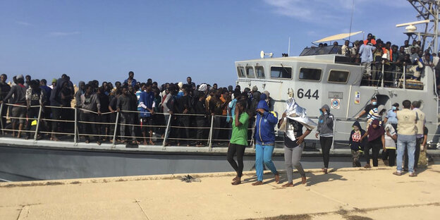 Schwarzafrikaner auf einem überfüllten Schiff; ein paar sind bereits an Land gegangen Schwarzafrikaner auf einem überfüllten Schiff; ein paar sind bereits an Land gegangen