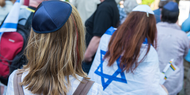 Zwei Kippa tragende Mädchen von hinten, eine davon hat sich in eine Israel-Fahne eingehüllt Zwei Kippa tragende Mädchen von hinten, eine davon hat sich in eine Israel-Fahne eingehüllt