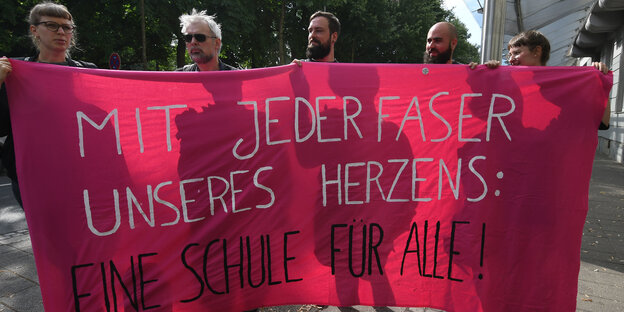 Fünf Studierende halten ein Transparent. Darauf steht: "Mit jeder Faser unseres Herzens: Eine Schule für alle". Fünf Studierende halten ein Transparent. Darauf steht: "Mit jeder Faser unseres Herzens: Eine Schule für alle".