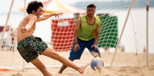 Männer spielen am Strand der Wolga Fußball.
