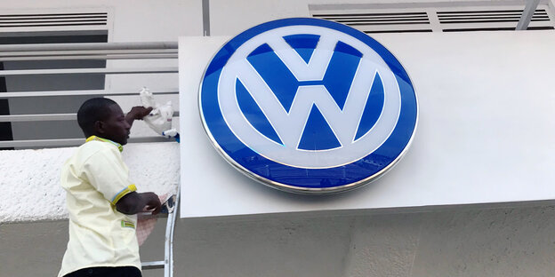 Ein Mann putzt das VW-Logo über dem nagelneuen Werk in Ruanda Ein Mann putzt das VW-Logo über dem nagelneuen Werk in Ruanda