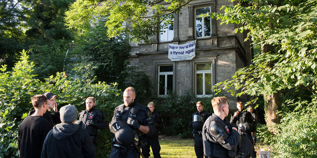 Mehrere Polizeibeamte mit Helmen und Schutzwesten stehen vor einem alten Haus Mehrere Polizeibeamte mit Helmen und Schutzwesten stehen vor einem alten Haus