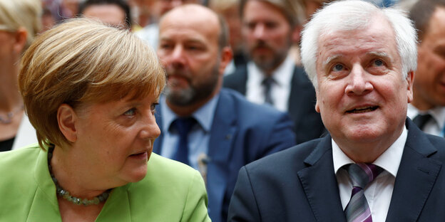 Merkel, im apfelgrünen Sakko, beugt sich fragend zum neben ihr sitzenden Seehofer, der guckt nach oben Merkel, im apfelgrünen Sakko, beugt sich fragend zum neben ihr sitzenden Seehofer, der guckt nach oben