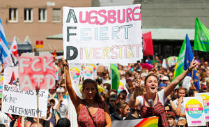 Demonstrant*innen halten in Augsburg bunte Schilder gegen die AfD hoch, unter anderem mit dem Slogan „Augsburg feiert Diversität“ Demonstrant*innen halten in Augsburg bunte Schilder gegen die AfD hoch, unter anderem mit dem Slogan „Augsburg feiert Diversität“
