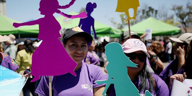 Frauen halten bunte, weibliche Figuren, die an Stäbe geklebt sind Frauen halten bunte, weibliche Figuren, die an Stäbe geklebt sind