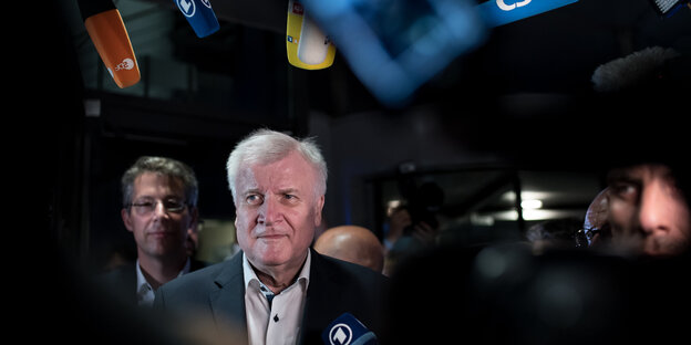 Unionsstreit - CSU-Chef Seehofer vor dunklem Hintergrund, Mikrophone um ihn rum Unionsstreit - CSU-Chef Seehofer vor dunklem Hintergrund, Mikrophone um ihn rum