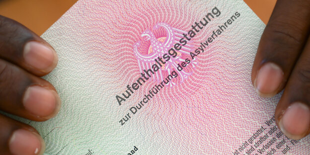 Ein somalischer Flüchtling hält eine Aufenthaltsgestattung in den Händen Ein somalischer Flüchtling hält eine Aufenthaltsgestattung in den Händen