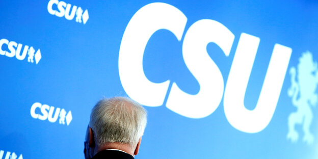 Seehofers Kopf von hinten vor einer Wand mit großem CSU-Schriftzug Seehofers Kopf von hinten vor einer Wand mit großem CSU-Schriftzug