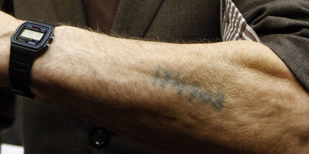 Ein Arm auf dem eine Nummer eintätowiert wurde von den Nazis. Er gehört einem ehemaligen Häftling des Konzentrationslagers Ausschwitz-Birkenau Ein Arm auf dem eine Nummer eintätowiert wurde von den Nazis. Er gehört einem ehemaligen Häftling des Konzentrationslagers Ausschwitz-Birkenau