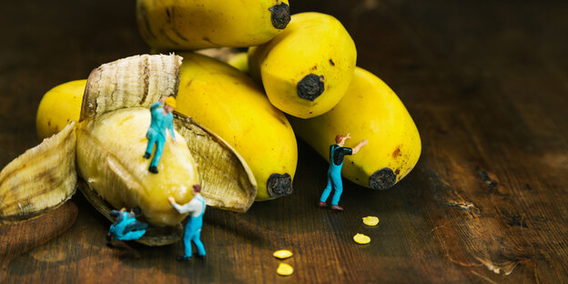 Kleine Spielfiguren klettern auf Bananen herum Kleine Spielfiguren klettern auf Bananen herum