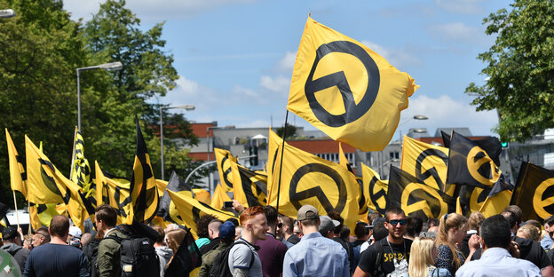 Personen stehen mit Fahnen der Identitären Bewegung auf der Straße Personen stehen mit Fahnen der Identitären Bewegung auf der Straße