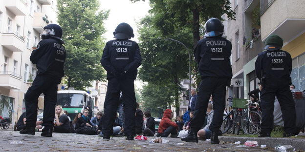 Eine Reihe Polizisten steht vor auf der Straße sitzenden Menschen Eine Reihe Polizisten steht vor auf der Straße sitzenden Menschen
