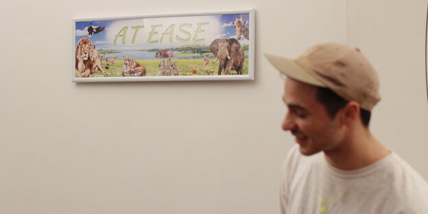 Mann mit Basecap steht neben einem Bild Mann mit Basecap steht neben einem Bild