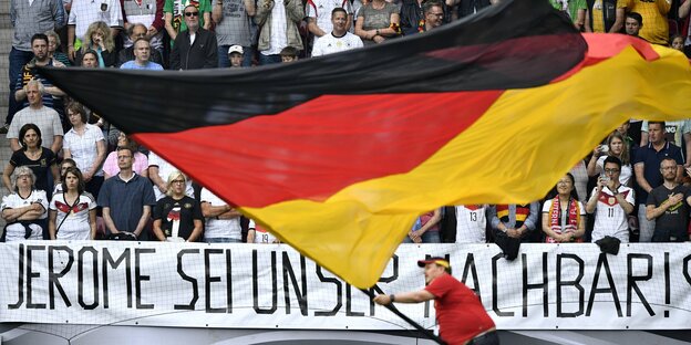 Jemand schwenkt die deutsche Fahne über einem Transparent: "Jerome sei unser Nachbar" Jemand schwenkt die deutsche Fahne über einem Transparent: "Jerome sei unser Nachbar"