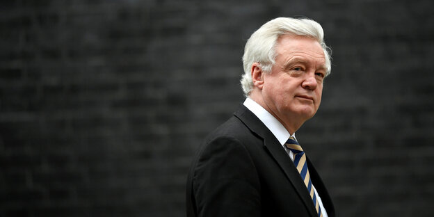 David Davis trägt einen Anzug und schaut skeptisch