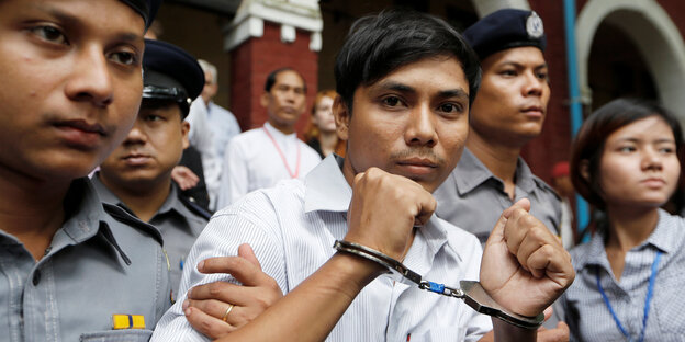 Der Journalist Kyaw Soe Oo ist in Handschellen und wird von Polizisten eskortiert Der Journalist Kyaw Soe Oo ist in Handschellen und wird von Polizisten eskortiert