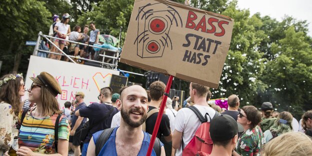 Ein junger Mann steht in einer Menschenmenge und trägt ein Schild mit der Aufschrift: „Bass statt Hass“ Ein junger Mann steht in einer Menschenmenge und trägt ein Schild mit der Aufschrift: „Bass statt Hass“