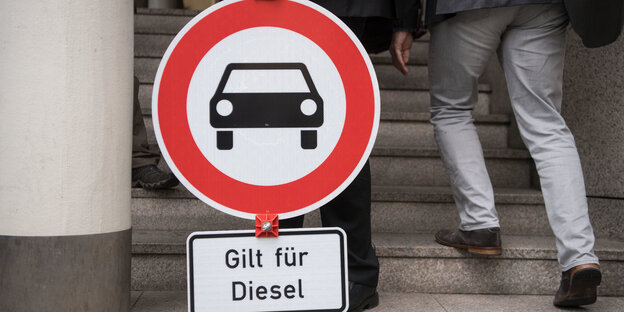Jemand trägt ein Straßenschild, auf dem steht: Gilt für Diesel Jemand trägt ein Straßenschild, auf dem steht: Gilt für Diesel