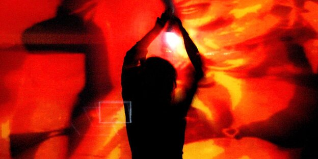 Silhoutte eines Menschen vor einer rot-verschwommenen Leinwand Silhoutte eines Menschen vor einer rot-verschwommenen Leinwand