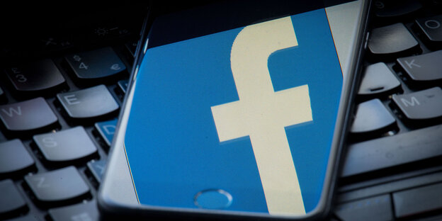 Ein Smartphone mit Facebook-Logo liegt auf einem Laptop Ein Smartphone mit Facebook-Logo liegt auf einem Laptop