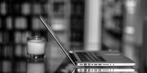 Ein Laptop steht neben einer Kerze auf einem Tisch Ein Laptop steht neben einer Kerze auf einem Tisch